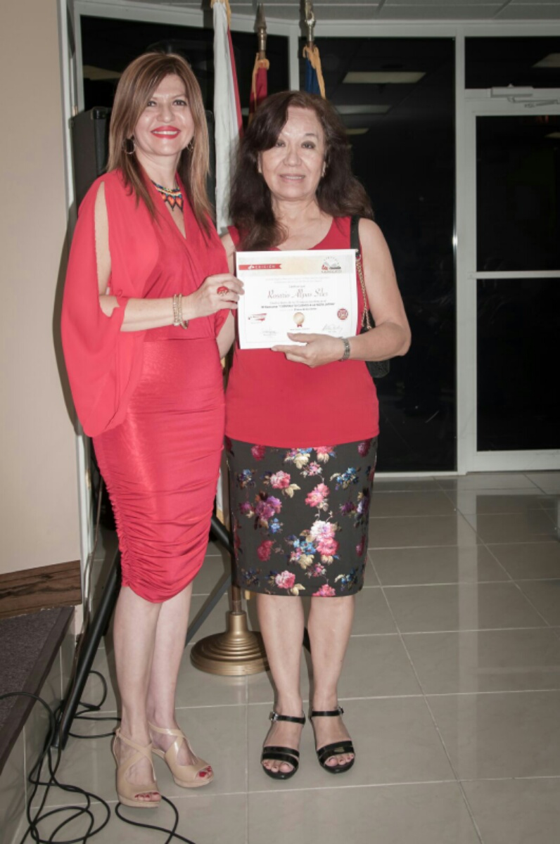 La escritora Rosario Allpas recibe de Marybel Torres su reconocimiento como finalista del concurso.