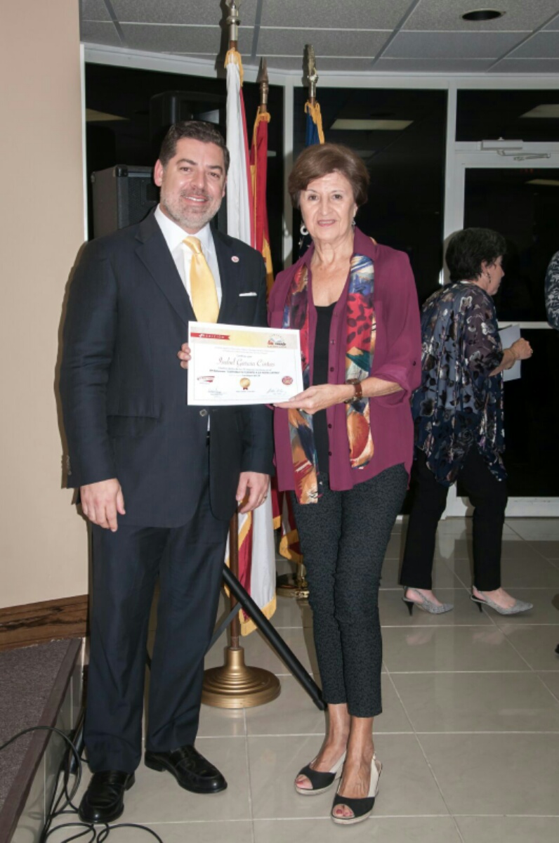 La escritora Isabel Cintas recibe de Carlos Montes de Oca su reconocimiento como finalista del concurso.