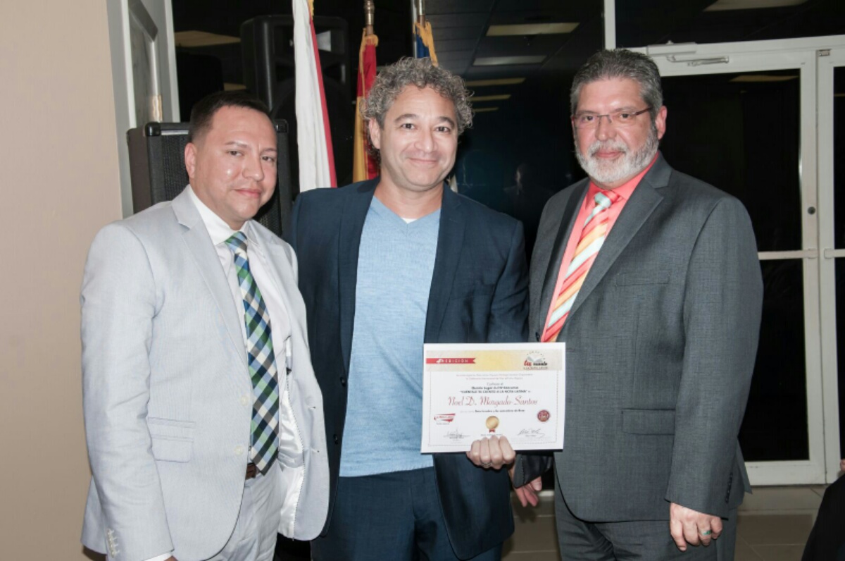 El escritor Noel Morgado-Santos, recibe su reconocimiento como ganador del quinto lugar por parte del Rector del Sistema Educativo Ana G Méndez, Luis Burgos y de Derick Toro, presidente de Family Life Care Services.